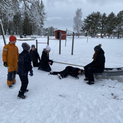 Barn som deltar i limbo ute i snön.