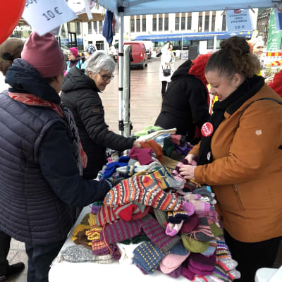 Ihmisiä tutkimassa tarjolla olevia villasukkia Turun kauppatorilla Nenäpäivän tapahtumassa.