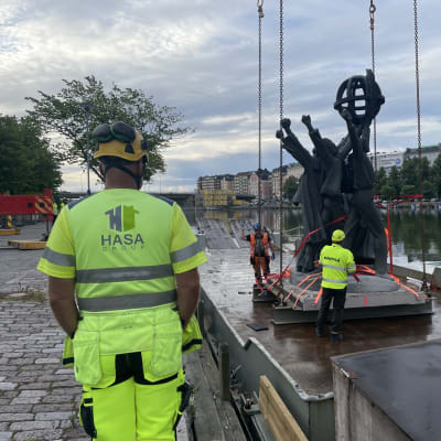 Statyn Världsfreden flyttas från Hagnäs och lyfts ombord på en pråm med hjälp av lyftkran. 