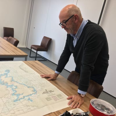 Ordföranden för det holländska fiskarförbundet böjer sig över en karta över Storbritannien i sitt arbetsrum.