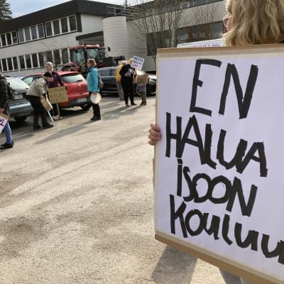 Mielenosoitus Ulvilan kaupungintalolla koululakkautuksia vastaan. Vanhemmilla kylttejä kädessä.