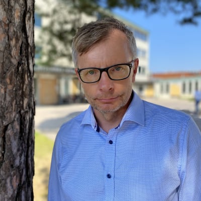 Heikki Hiilamo, forskningsprofessor vid THL, bredvid ett träd utanför jobbet. 