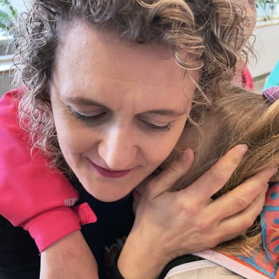 Vapaaehtoinen Elina Viljamaa halaa ukrainalaista lasta. 