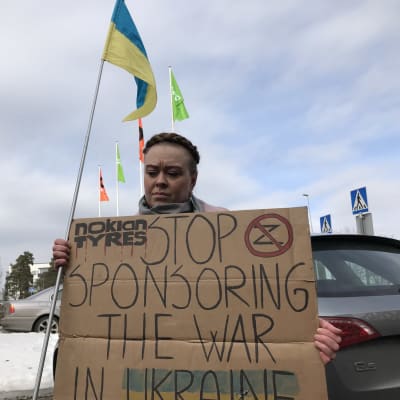 Mielenosoittaja kyltin kanssa: Stop sponsoring the war in Ukraine.