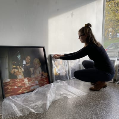 Linda Varoma poistaa kuplamuovia teoksen ympäriltä galleriassa.