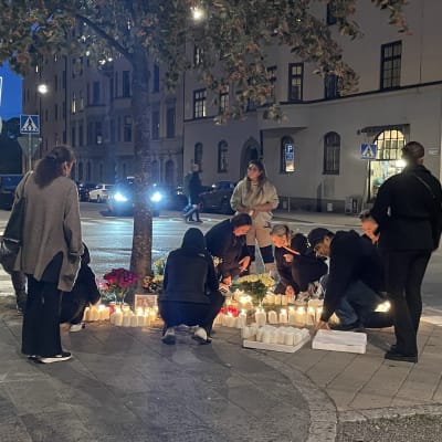Nuoret asettelevat kukkia ja kynttilöitä paikalle, jossa 19-vuotias mies ammuttiin kuoliaaksi. 