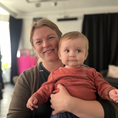 En mamma med en baby i famnen.