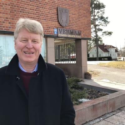 Ari Koskinen hymyilee vapautuneesti Vehmaan kunnanviraston edustalla.