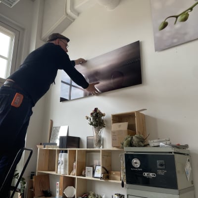 Valokuvataiteilija Vesa Aaltonen kiinnittää taulua seinälle Turun Taiteen talossa. 