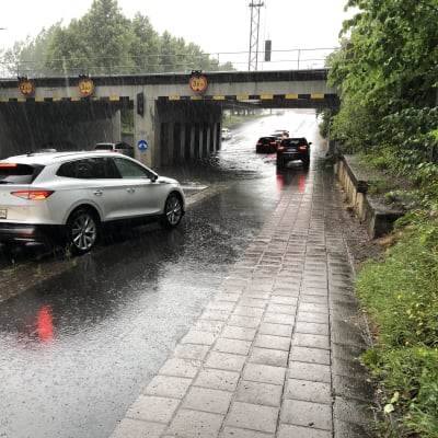 Auto ajaa sillan alle. Sillan alla iso vesilätäkkö.