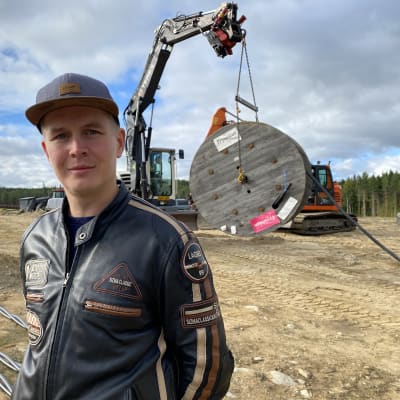 Sulkavan kunnan kiinteistöpäällikkö Antti Hulkkonen henkilökuvassa. Takaalalla maansiirtokone ja sähkökaapelia.