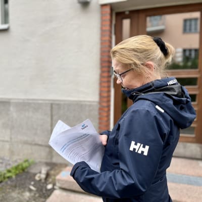 En person i blå jacka som tittar igenom en pappersbunt.