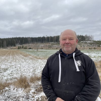 Mies seisoo. Taustalla metsikkö, joka on Venäjän puolta. Välissä pelto. 
