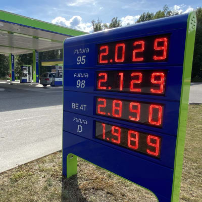 Sini-vihreä tankkausaseman kyltti, jossa punaisilla valokirjaimilla bensan ja dieselin hintoja. Pienin hinta dieselin 1 euroa ja 989 senttiä.