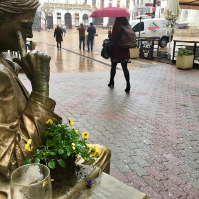 En kvinna går förbi en staty av en man som ser ut att titta på henne bakifrån