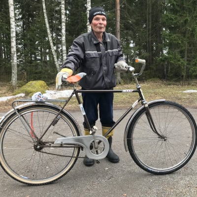 Håkan Weckström vid sin cykel, skog i bakgrunden.