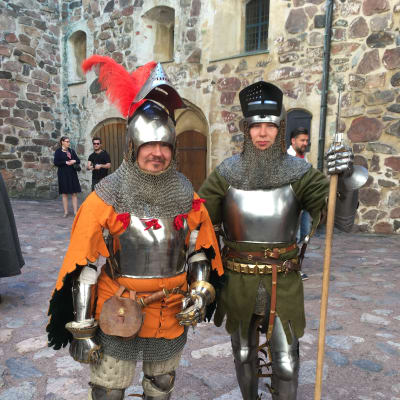 Två skådespelare står i soldatkostym från medeltiden. 