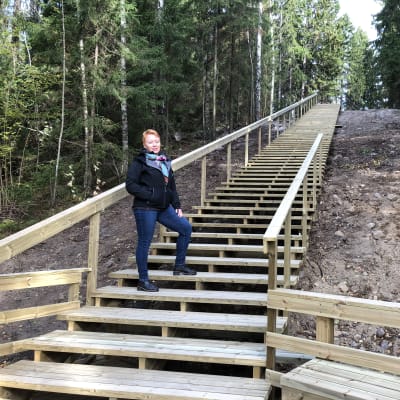 En kvinna står halvvägs uppför trappa.