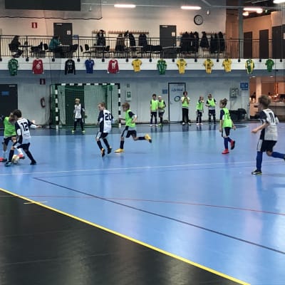 Unga pojkar spelar fotboll i en hall.