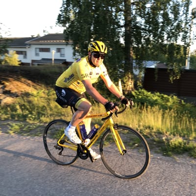 Christer Holmlund cyklar på en cykel. Han har färgglada cykelkläder på sig.