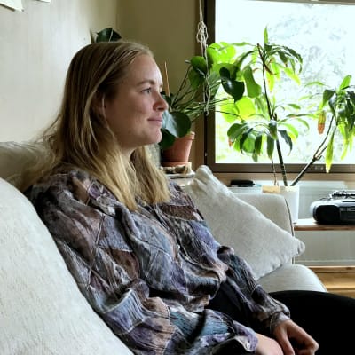 kvinna sitter i en soffa i sitt vardagsrum med växter runtom