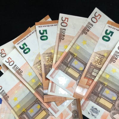 Flera 50 euros sedlar utspridda över svart bakgrund