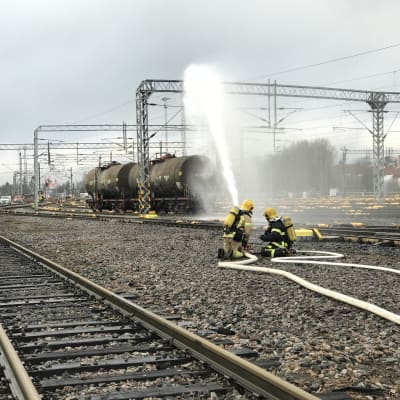 Palomiehet ruiskuttavat vettä Tampereen ratapihalla.