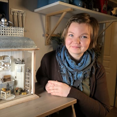 Salla Heikkilä med en lykta som är inredd med miniatyrmöbler