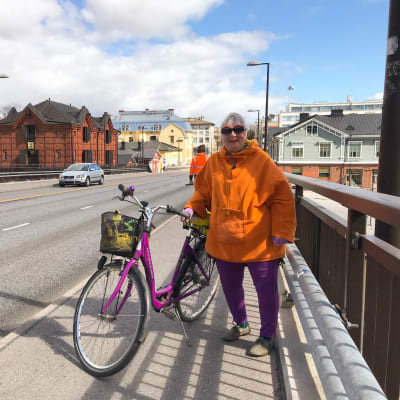 En kvinna med sin cykel på Mannerheimgatans bro.