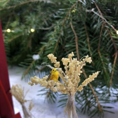 En julkärve i miniatyr i vilken det sitter en gulsparv i miniatyr.
