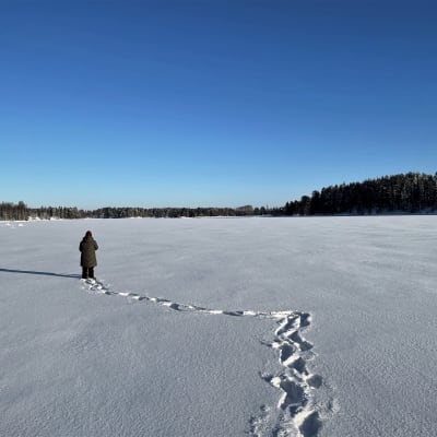 Nainen kävelee järven jäällä.