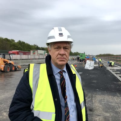 Marc Dillen från den flamländska byggindustrins branschorganisation står framför ett stort brobygge utanför Gent. 