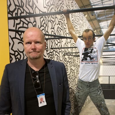 Mies seisoo valokuvan edessä näyttelyssä