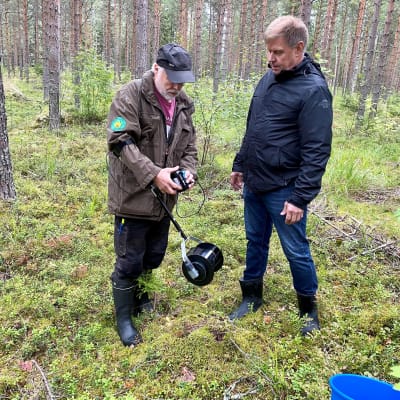 Mies esittelee toiselle akkukäyttöistä, varrellista marjanpoimuria 