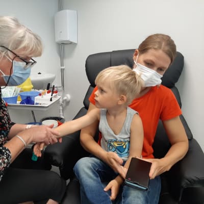 Pojke tittar på en vårdare som precis ska ge honom vaccin.