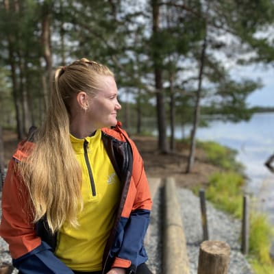 Liikunnanohjaaja Satu Suomalainen istuu nuotiopaikalla Luutalammin rannalla.