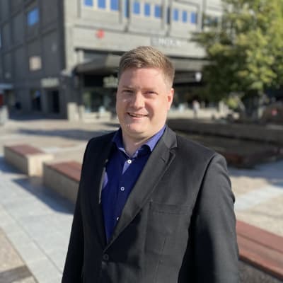 Mansantagen person poserar på torg.