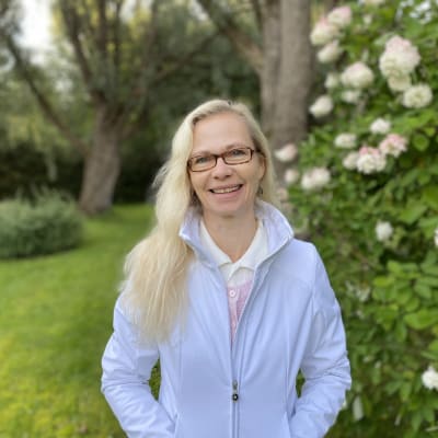 Suomen kasvukäytäverkoston johtaja Jaana Villanen pihalla hortensiapensaan edessä