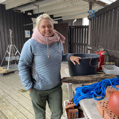 Ilse Klockars står vid ett bord med en hink och bojar. 