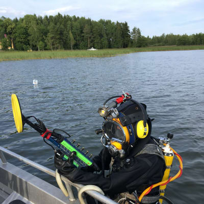 Dykare i vattnet bredvid motorbåt
