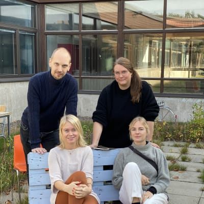 En man och tre kvinnor sitter på en bänk utomhus.