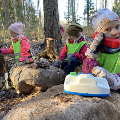 Neela Houni, Sointu Hämäläinen ja Iines Junnila leikkivät syksyisessä metsässä. Etualalla Junnila puhuu leikkipuhelimessa.