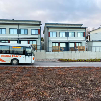 En buss kör förbi tre radhus.