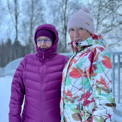 Kaksi naista seisoo sillalla talvisessa maisemassa.