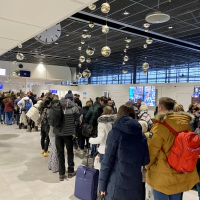 Rovaniemen lentokentällä ihmisiä jonossa turvatarkastukseen. 