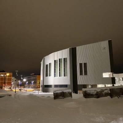Rovaniemen kaupungintalo hämärässä illassa. Maassa on lunta. 