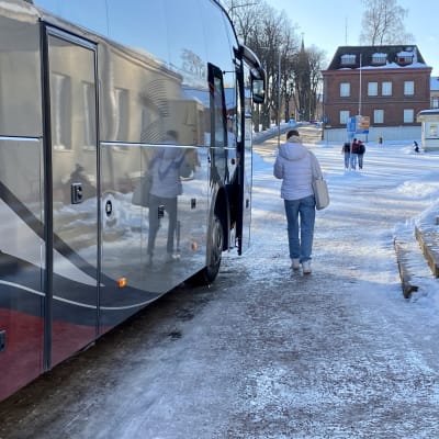 En buss står vid Lovisa busstation med riktning mot Borgå. En ung kvinna som är på väg mot bussen syns bakifrån.