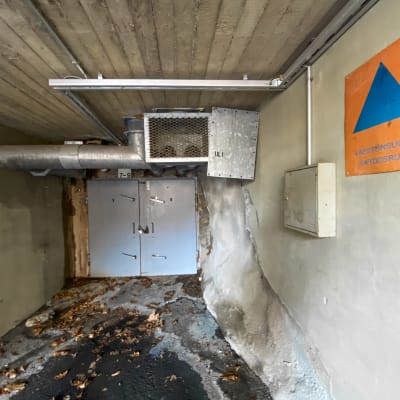 Ingången till ett bergskydd, i förgrunden en skyddsrumsskylt.
