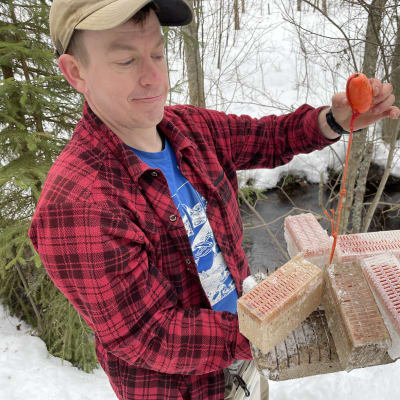 Limnologi Heikki Holsti esittelee valmista viiden mätirasian ja painokiven pakettia, joka laitetaan takana näkyvään ojaan.