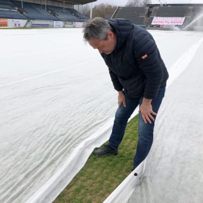 Liikuntapaikkamestari Jukka Virtanen katsoo Kupittaan jalkapallostadionin nurmen tilaa.